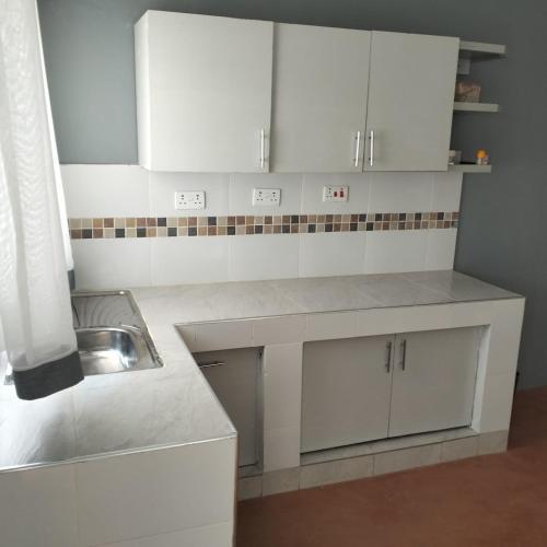 una cocina blanca con fregadero y armarios blancos en Casa Nostra funyula, en Nangina