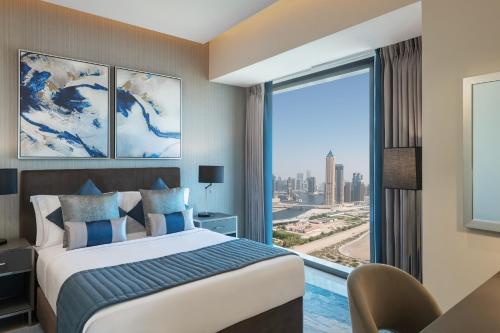 a hotel room with a bed and a large window at DAMAC Maison Aykon City Dubai in Dubai
