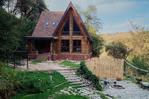 una cabaña de madera con una valla delante en Sabay Sai Wooden Guesthouse in The National Park en Almaty