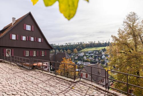 a red house on a hill with a town in the background at Ferienwohnungen Metzgerpost in Altensteig