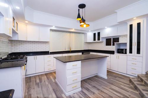 a kitchen with white cabinets and a black counter top at Enashipai Holiday Homes in Makandara