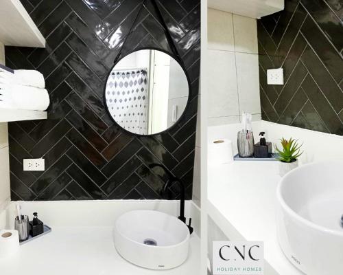 ein Badezimmer mit einem weißen Waschbecken und einem Spiegel in der Unterkunft CNC Tagaytay Staycation with Netflix in Tagaytay