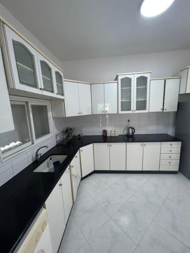 una gran cocina con armarios blancos y encimeras negras en Casa de Galilee en Tiberias