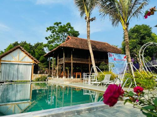 a resort with a swimming pool and palm trees at Nha Ben Ho Venuestay in Hanoi
