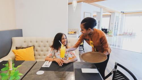 a boy and a girl sitting at a table at Hotel Suni Sentani - Managed by East Season in Jayapura