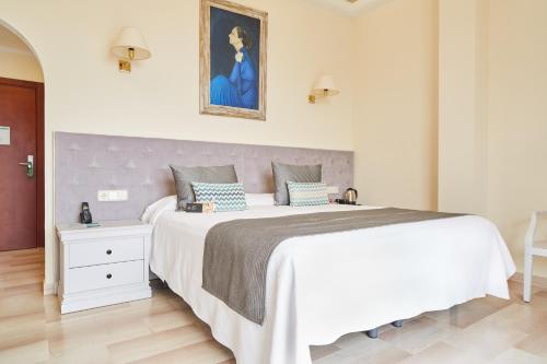 a bedroom with a large white bed and a painting on the wall at Grand Hotel Palladium Santa Eulalia del Río in Santa Eularia des Riu