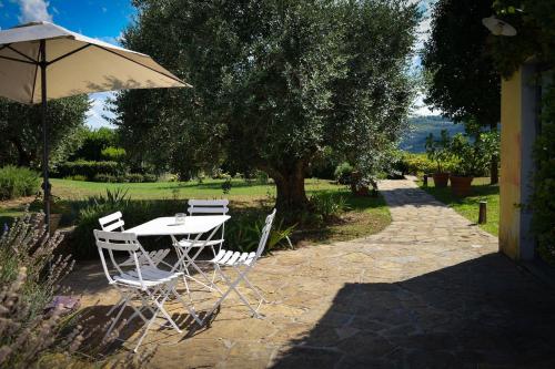a table and chairs under an umbrella on a patio at Dante Country House - Casa con Piscina Privata e Jacuzzi tra Firenze e Chianti in Scandicci