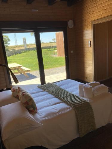 a large bed in a room with a large window at A Quinta de Bouzas in Mazaricos
