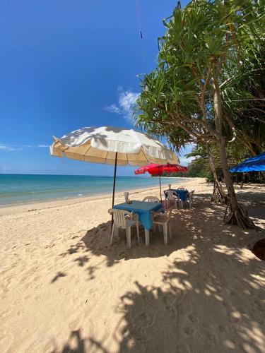 a table and chairs under an umbrella on a beach at Ruan Mai Naiyang Beach Resort in Nai Yang Beach