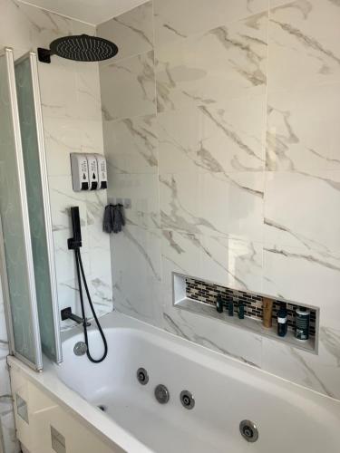 a bathroom with a white tub with a shower at Large guest Room in Maidenhead