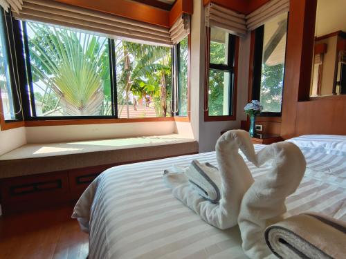 Baan Natcha Villa في باتايا سنترال: غرفة نوم مع سرير مع مناشف الحيوانات عليه