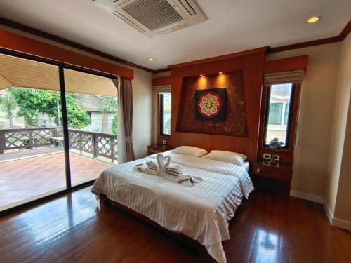 a bedroom with a large bed and a balcony at Baan Natcha Villa in Pattaya Central