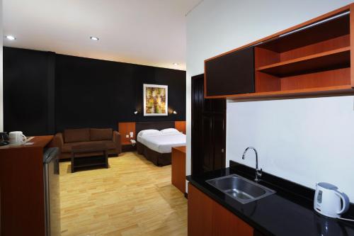 um quarto de hotel com uma cama e uma cozinha com um lavatório em ARCS House Menteng by Jambuluwuk em Jakarta