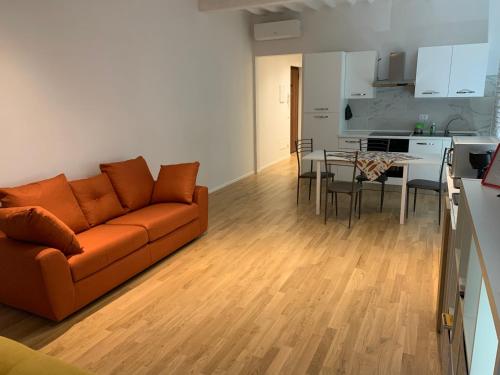 a living room with an orange couch and a kitchen at LA PICCOLA MAGIA in Pisa