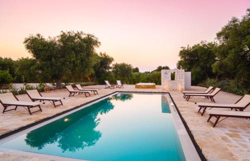 een zwembad met ligstoelen en een tafel bij Tenuta Fonte in Ostuni
