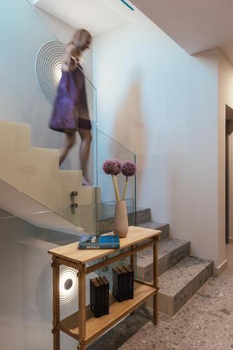 a woman walking down a staircase with a table and flowers at Boutique hotel MaViE - Adults Only in Neum