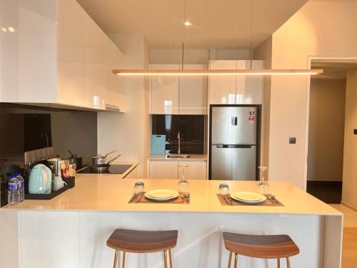 una cucina con bancone, 2 sedie e frigorifero di Star KLCC By Cozy White a Kuala Lumpur