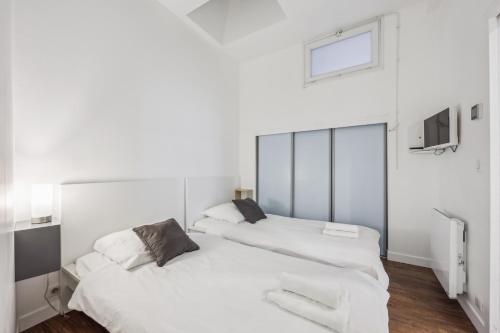 2 łóżka w pokoju z białymi ścianami w obiekcie Appartement charmant et lumineux en plein cœur de Paris w Paryżu