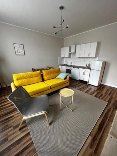 a living room with a yellow couch and a kitchen at Lodging Młyńska Parking free in Bielsko-Biała