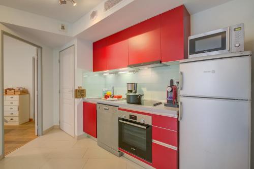 une cuisine avec des armoires rouges et un réfrigérateur blanc dans l'établissement Au Vieux Port Cannes City Center - Happy Rentals, à Cannes
