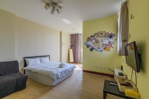 a bedroom with a bed and a tv and a couch at Fengjia Love I Hostel in Taichung