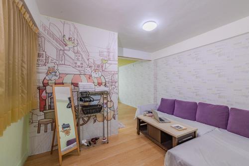 a living room with a purple couch and a mural at Fengjia Love I Hostel in Taichung