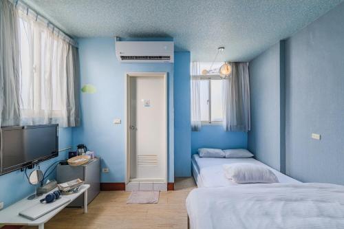 a blue room with two beds and a television at Fengjia Love I Hostel in Taichung