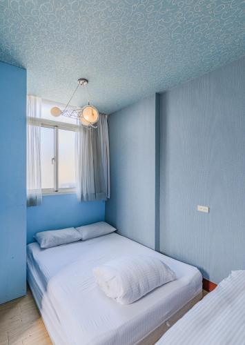 a blue room with two beds and a window at Fengjia Love I Hostel in Taichung