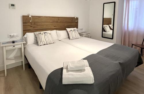a bedroom with a large white bed and a mirror at 7 Kale Bed and Breakfast in Bilbao