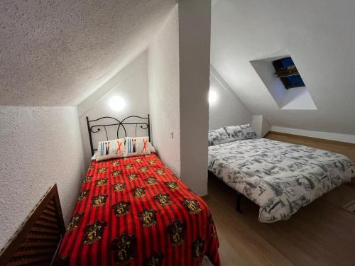 Apartamento esqui montaña Cofiñal في Cofiñal: غرفة نوم بسريرين وبطانية حمراء