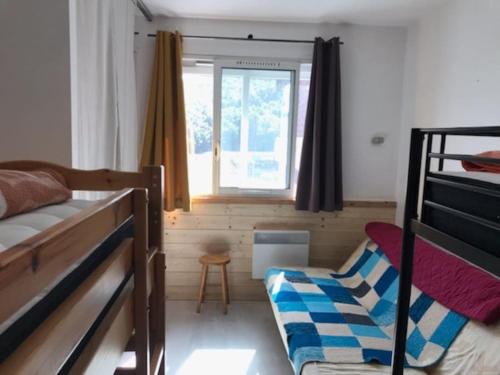 a bedroom with two bunk beds and a window at appartement 6 places station super besse in Besse-et-Saint-Anastaise