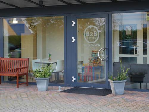 a store window with a bench in front of it at B&B Hotel Berlin-Süd Genshagen in Ludwigsfelde