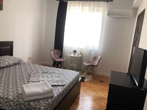 a bedroom with a bed and a window with two chairs at Studio Central Doamnei in Bucharest