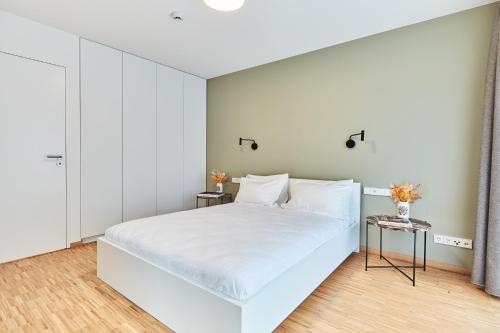 a white bedroom with a large bed with white walls at Résidence du Lys - Perrin Apartments in Luxembourg