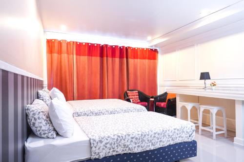 a bedroom with two beds and an orange curtain at Guesthouse Phuket Airport in Ban Bo Han