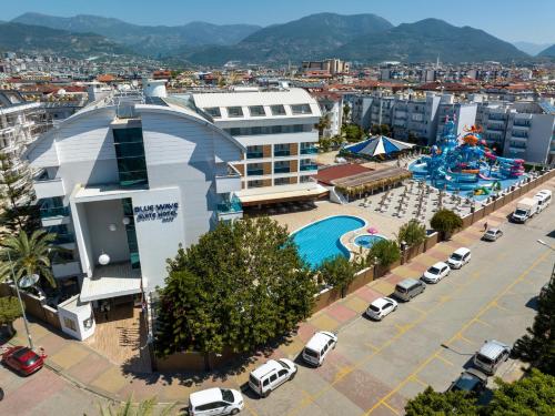 een gebouw met een zwembad en een parkeerplaats met auto's bij Blue Wave Suite Hotel in Alanya