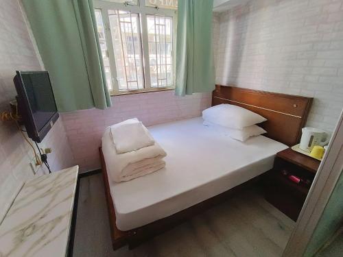 a small bed in a small room with a window at Tempo Inn@ David Mansion in Hong Kong