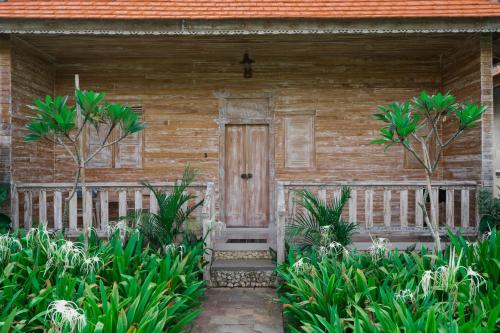 Agaru Villa Uluwatu by The Lavana في أُلُواتو: منزل خشبي مع باب خشبي وبعض النباتات
