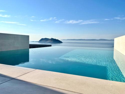 a swimming pool with a view of the water at Eleia Seafront Rooms & Villas in Petra