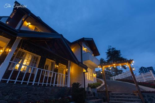 a house with lights on the porch at night at The Tapherini Bungalow in Nuwara Eliya