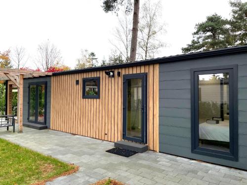 a small house with wooden siding on a patio at SERENDIPITY - nature in luxury in Beekbergen