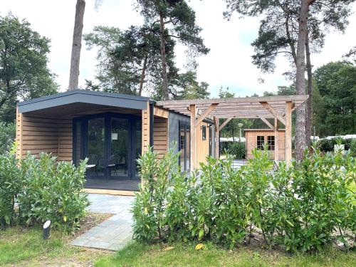 una pequeña casa de madera con techo negro en Luxe Bos Cottage SERENDIPITY, en Beekbergen