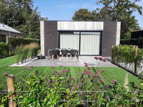 a garden with four chairs and a table in a house at Prachtige bungalow op vakantiepark bij zee. in Baarland