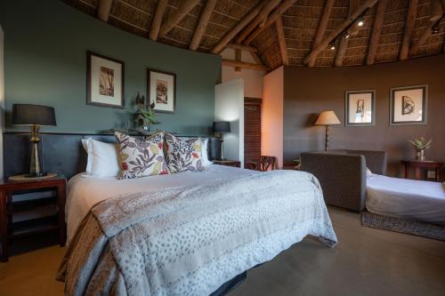 a bedroom with a large bed and a chair at Kuzuko Lodge in Addo