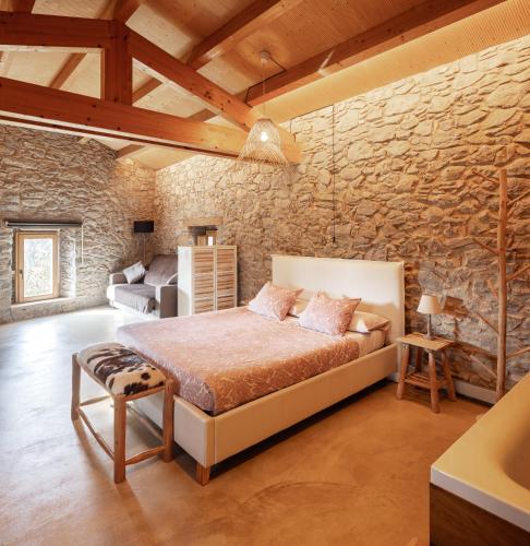 a bedroom with a bed and a stone wall at El Rebastral - Mas Vinyoles Natura in Sant Pere de Torelló