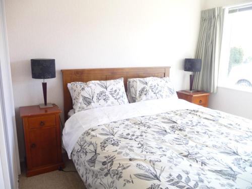 a bedroom with a bed and two lamps and a window at Warm & welcome on Whiteley in New Plymouth
