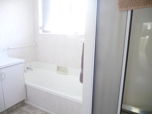 uma casa de banho branca com uma banheira e uma janela em Warm & welcome on Whiteley em New Plymouth
