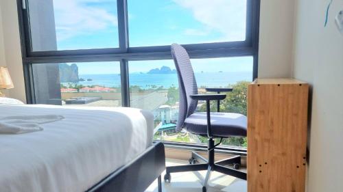 A404-nice Seaview One Bedroom At Ao Nang Beach في شاطيء آونانغ: غرفة نوم بسرير وكرسي امام نافذة