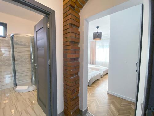 a bathroom with a glass shower and a brick wall at Vila Roza in Sighetu Marmaţiei