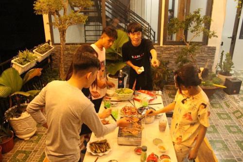 a group of people standing around a table with food at Nhà Nghĩ Homestay KV in Bình Thủy